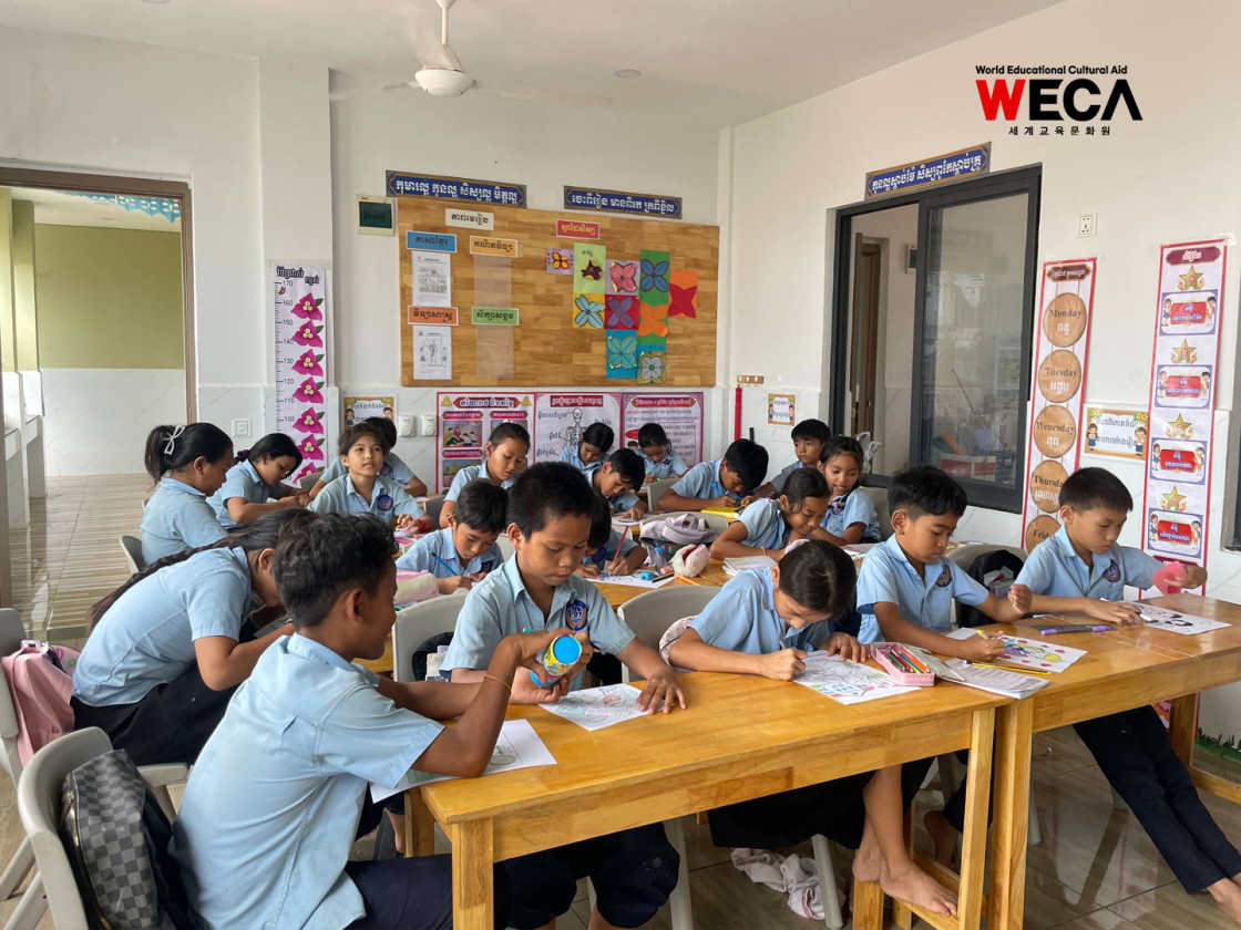 WECA 글로리아 초등학교 아이들이 영어문장이 적힌 종이에 그림을 색칠하며 영문장을 외우고 있는 모습