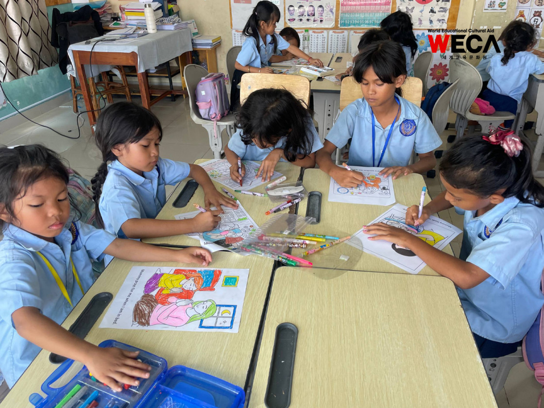 WECA 글로리아 초등학교 아이들이 영어문장이 적힌 종이에 그림을 색칠하며 영문장을 외우고 있는 모습