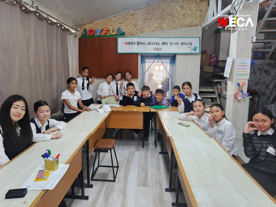 알마티 JOYFUL센터 교실에 옹기종기 모여 앉아 다 함께 다정한 포즈를 취하며 촬영한 한국어 수업반 단체 기념사진
