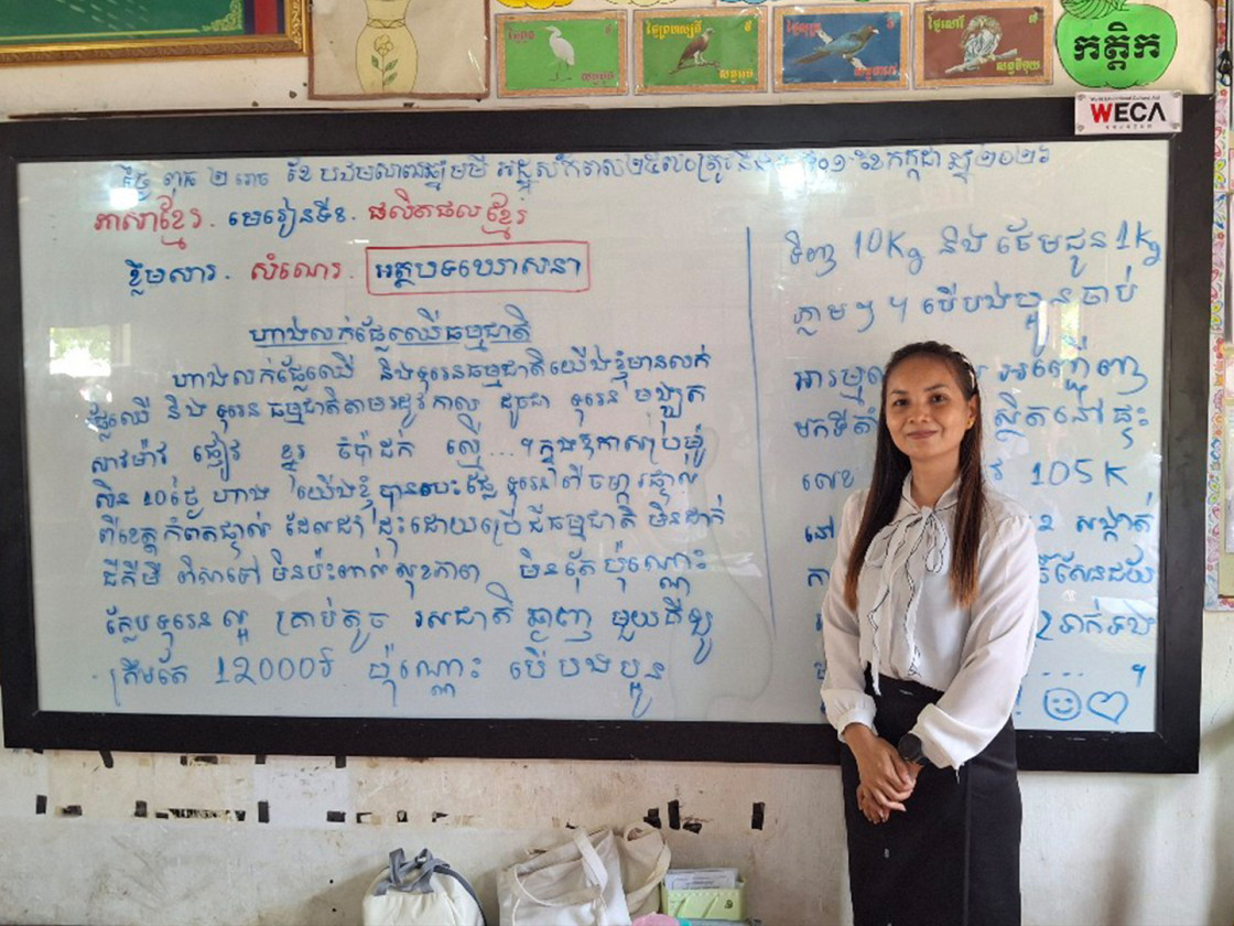 당꺼상초등학교 교실에서 선생님이 새로운 칠판 앞에서서 카메라를 보며 미소를 짓는 모습